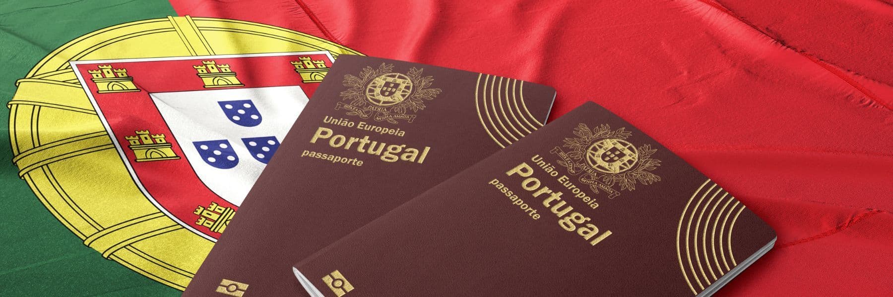 Two maroon Portuguese passports with gold lettering resting atop a draped Portuguese flag.