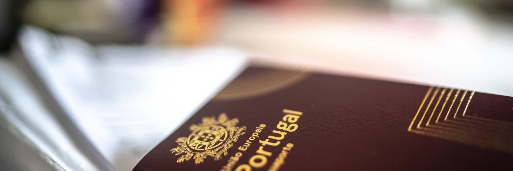 Portuguese passport on top of an open book, with gold emblem visible.